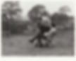 Black and white photo of men sat in folding chairs in front of fence