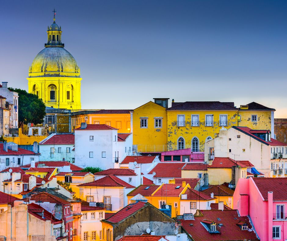 Colorful houses cluster around the National Pantheon Dome in the Alfama district of Lisbon, Portugal.