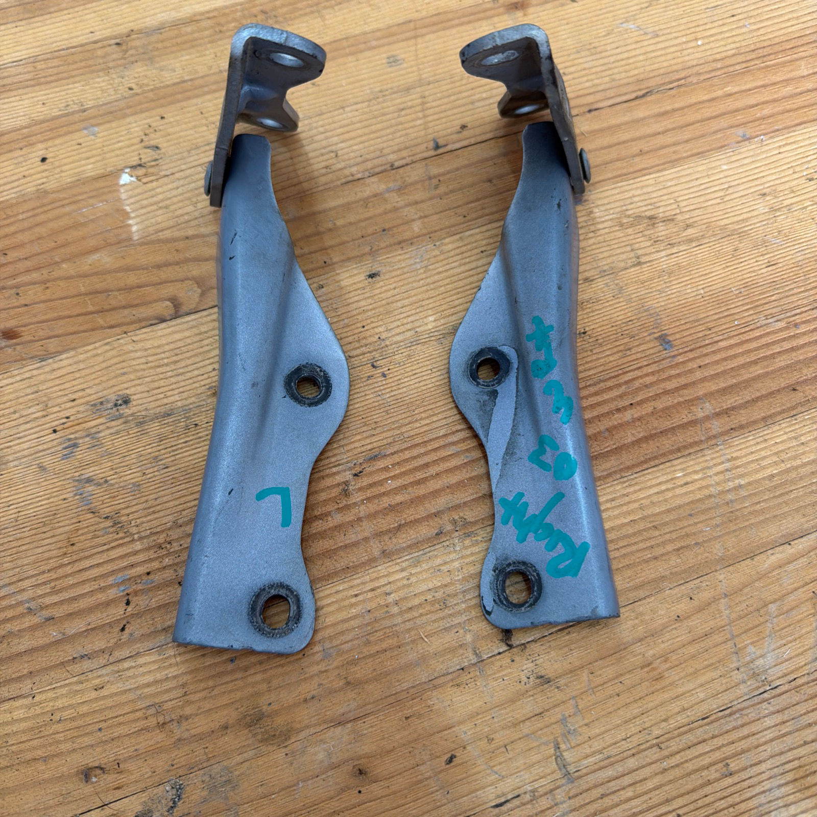 OEM 02-03 Impreza WRX hood hinges on a wooden surface.