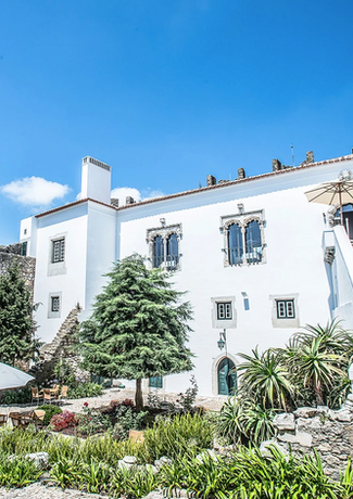 Green courtyard of a white old castle with stairs leading to the highest floor