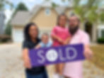 A happy family posing with a Sold by Colby sign in front of their new home