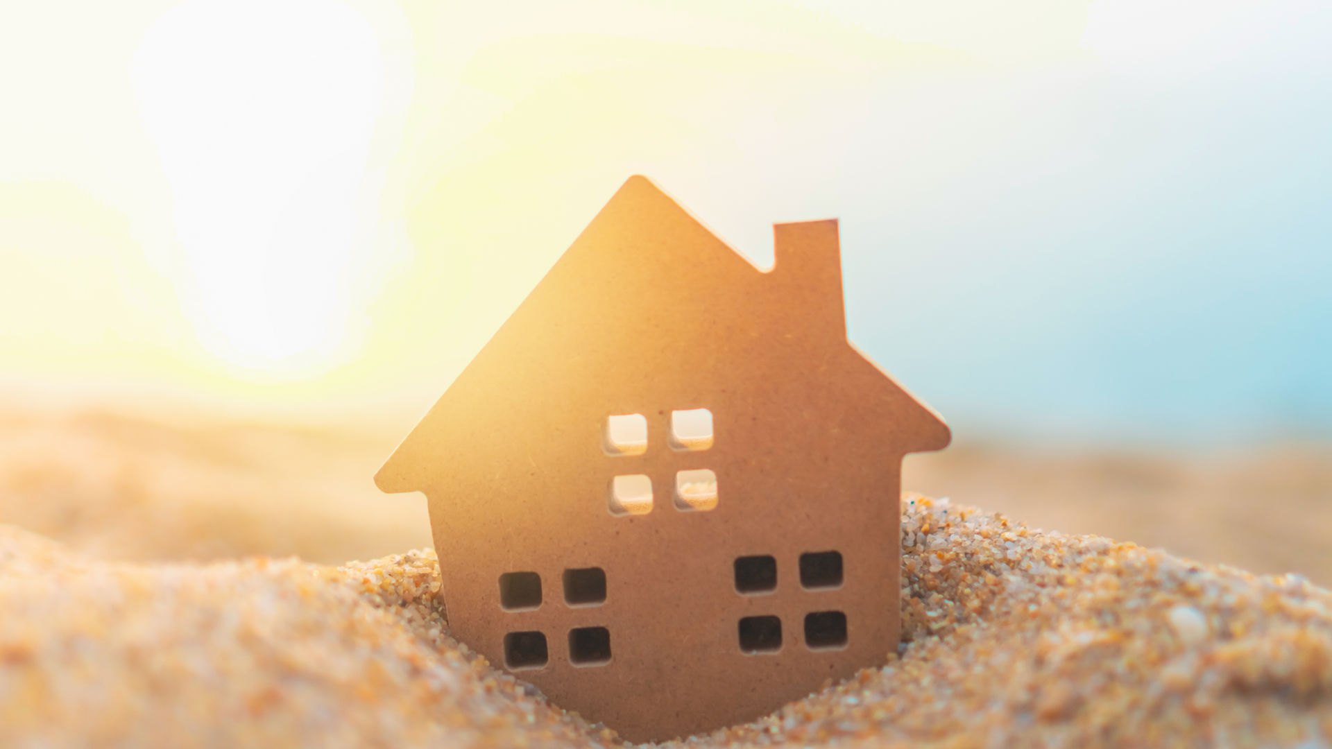 Small house figure on the beach at sunrise