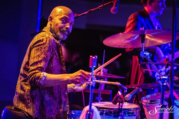 Drummer playing drums during a live show, stage lighting, musical performance, and Guilford Hall Brewery