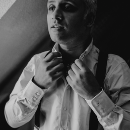Indian british groom getting ready before the wedding. He is adjusting his tie.