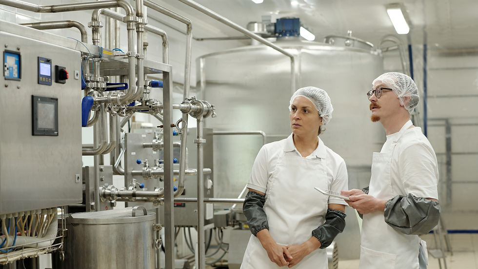 Manufacturing workers reviewing production equipment and controls on a factory floor, illustrating manufacturing risk management during periods of increased output.