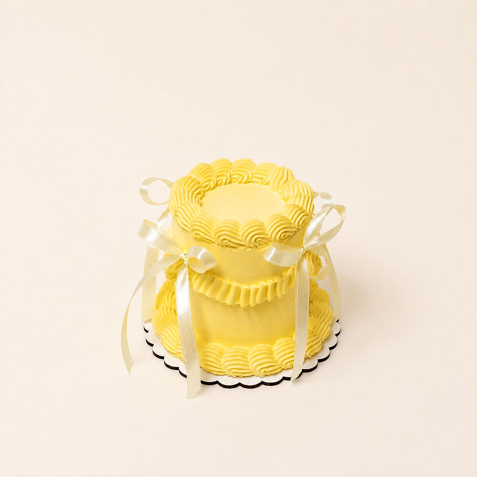 Vista tres cuartos del fake cake Limoncello Coquette con acabado amarillo mantequilla y decoración de crema artesanal.