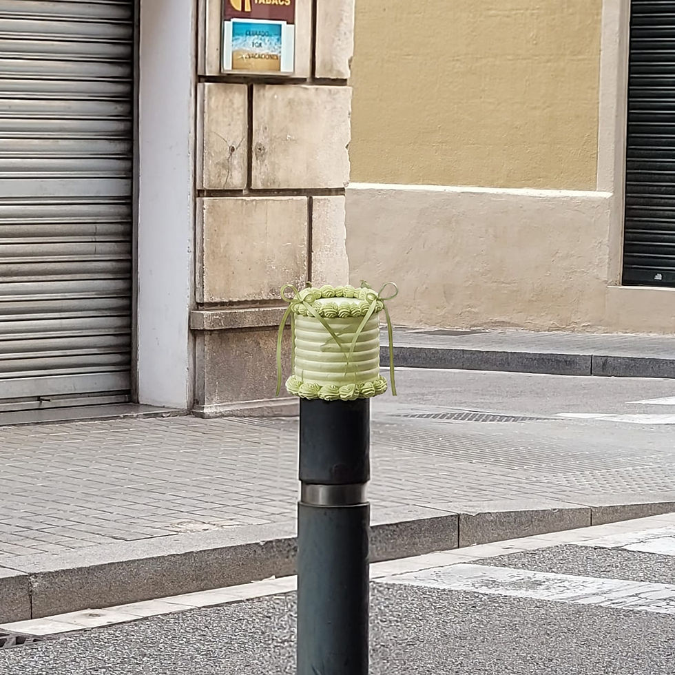 Pistachio Coquette colocado sobre un pivote negro en una calle de Barcelona. El pequeño pastel falso verde pistacho con lazos