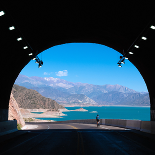 Ciclista saliendo de túnel, vista lago y montañas
