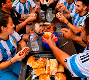 Grupo con camisetas de Argentina comiendo choripán.