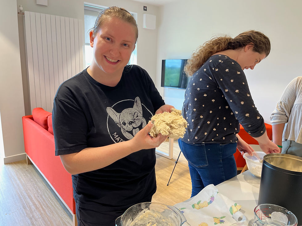 Woman looking at the camera holding a ball of pizza dough.