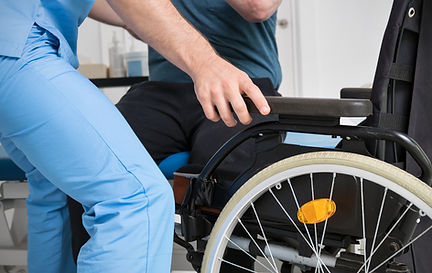 male-physiotherapist-helping-patient-with-disability-who-uses-wheelchair-get-up-rehabili.j