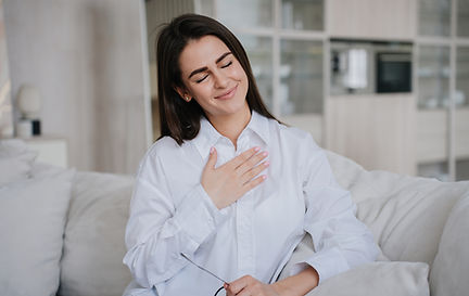 grateful-girl-eyes-closed-smiles-touches-chest-appreciate-gesture-sits-sofa-living-room.jp