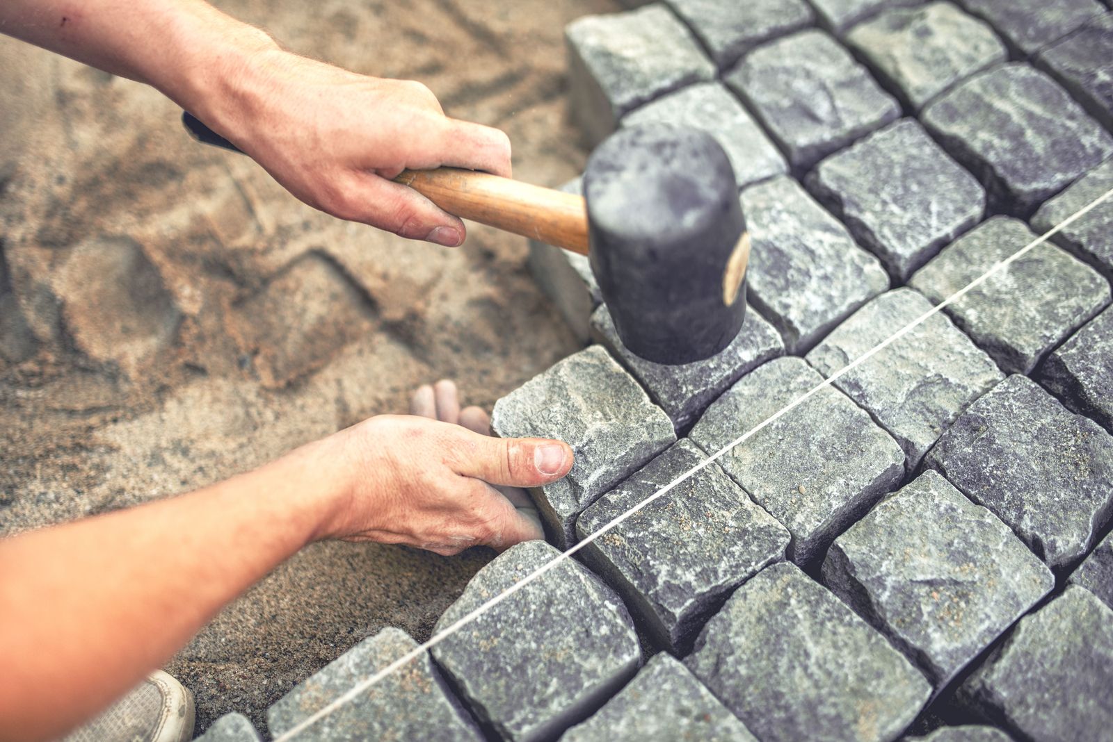 Worker installing pavers in an Austin landscape