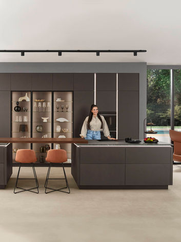 Modern bespoke matte kitchen showroom display with dual islands, illuminated shelving, and elegant seating, designed and installed by KV Designs in Leeds.