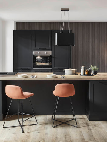 Modern bespoke black shaker-style fitted kitchen with a large island, warm wood countertop, and integrated appliances, designed and installed by KV Designs in Leeds.