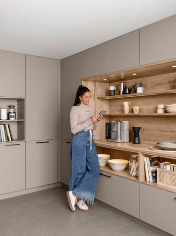 A custom-designed hidden coffee station in a bespoke kitchen, showcasing sleek pocket doors and integrated wood-finished shelving, installed by KV Designs in Leeds.