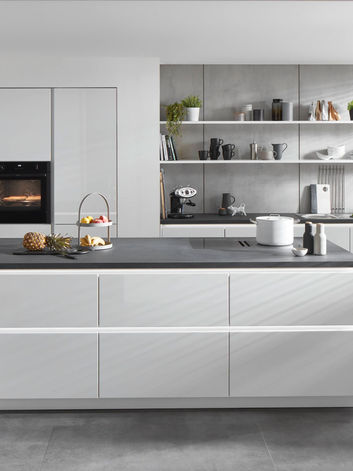 Modern bespoke high-gloss white fitted kitchen with central island and integrated appliances, designed and installed by KV Designs in Leeds.
