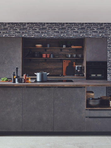 Bespoke luxury matte black fitted kitchen featuring integrated shelving and a striking textured stone wall, designed and installed by KV Designs in Leeds.