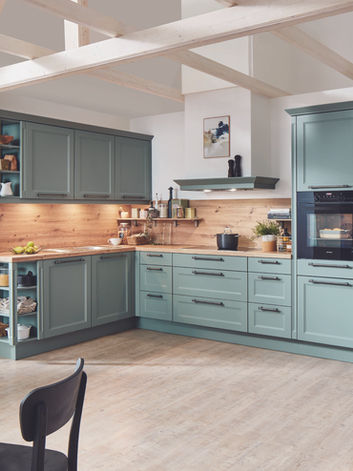 Modern bespoke kitchen with Senso soft-touch matt sage green cabinets, warm wood countertops, and integrated appliances, designed and installed by KV Designs in Leeds.