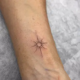 Minimalist fine line sun tattoo on the inner wrist by a professional tattoo artist in Budva.