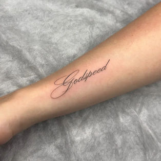 Elegant fine line Godspeed script lettering tattoo on forearm, done at a professional Budva tattoo studio.