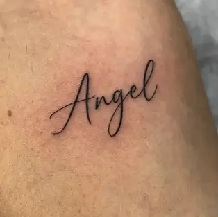 A delicate, minimalist "Angel" word tattoo in elegant cursive script, professionally inked at a tattoo studio in Budva