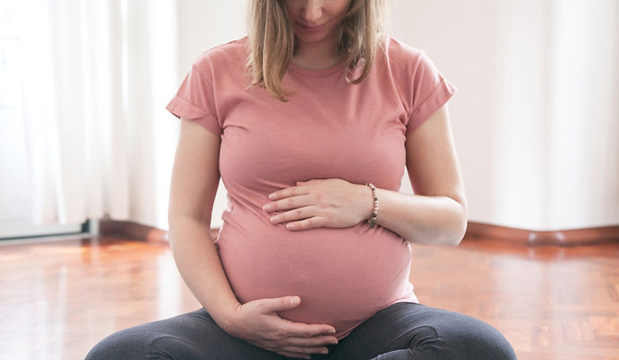 mulher grávida sentada e acariciando a barriga