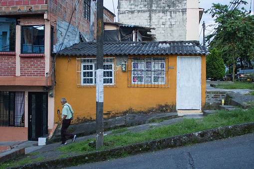 Yellow house in Pereira on a small hill with an old man walking by