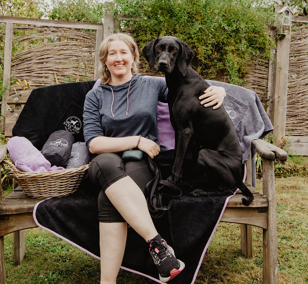 Bark and Beau Founder Leanne sits on a garden bench with her black german shorthaired pointer Darcy, surrounded by Bark and Beau Towels