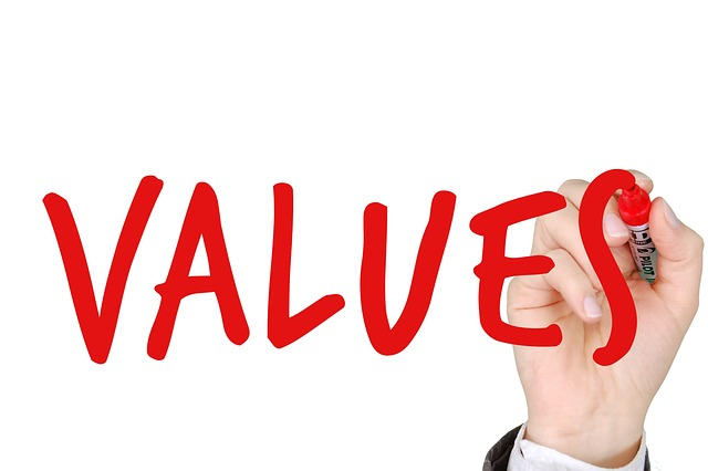 Photo of a hand with a red marker that has written "VALUES" on a board.