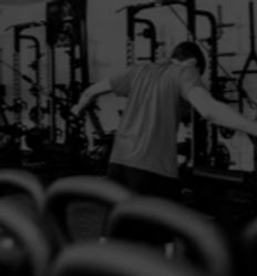 Black and white image of the back of a man as he lifts pulley-ed weights