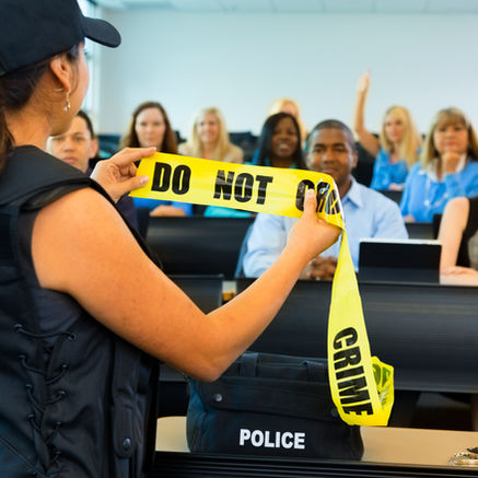 a female instructor teaching a policing class with a yellow crime scene tape.