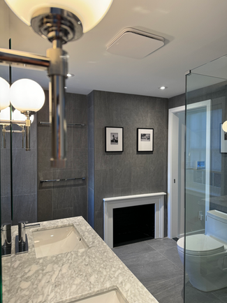 Modern bathroom with marble countertops and gray tiled wall.