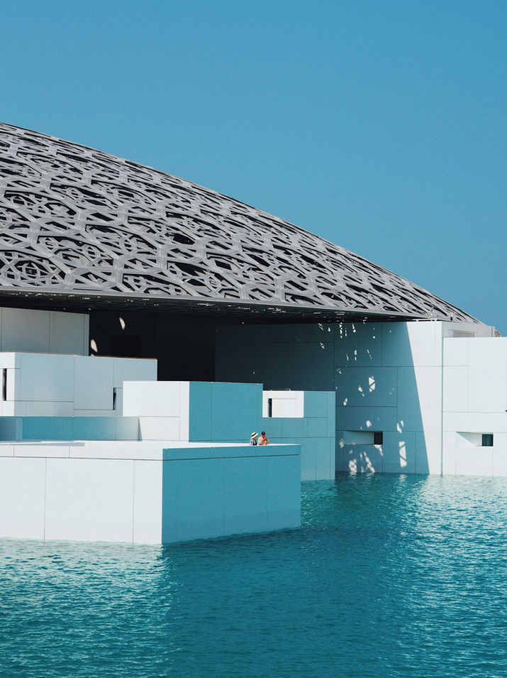 Architectural photography of the Louvre Abu Dhabi in the United Arab Emirates, capturing the iconic dome, geometric patterns, natural light, and the interaction between architecture, space, and visitors.