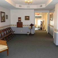 Empty waiting room with chairs, decorative wall border, framed art, light fixture.
