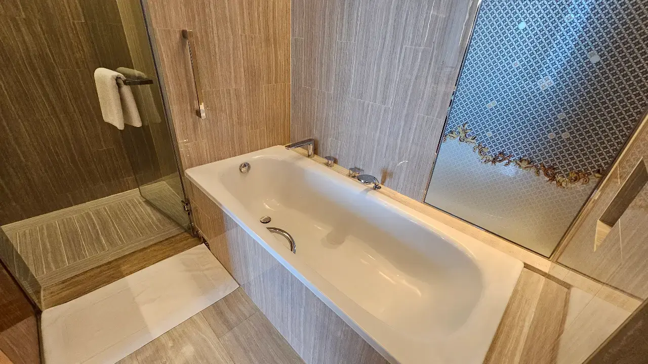 White bathtub beside a frosted window in our spacious hotel bathroom.