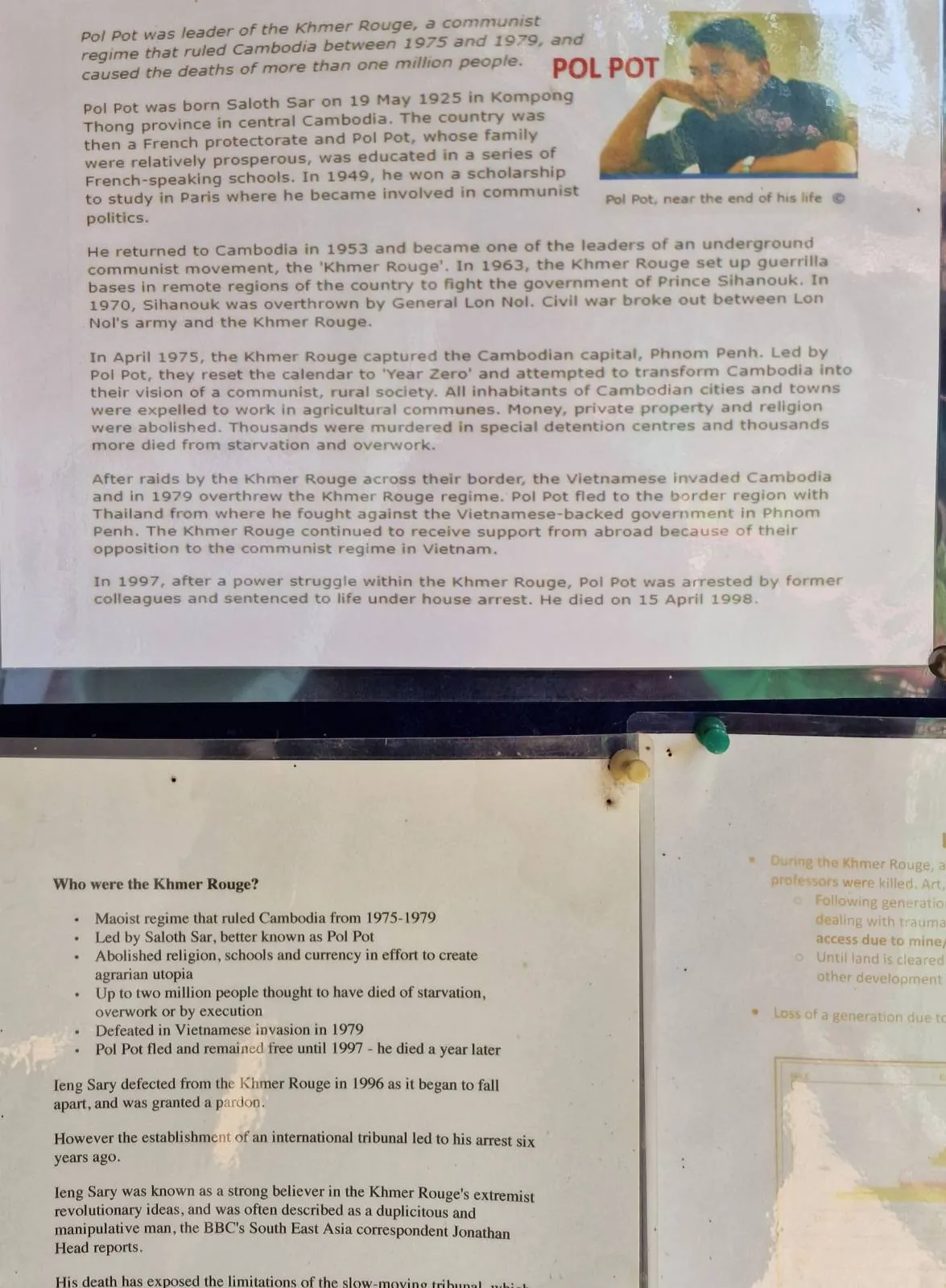 A printed article with text and a small photo of a person on the top right corner. Below, there are two more sections of text, partially visible, with bullet points and a map on the right. The content is posted on a notice board.