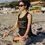 Thumbnail: A woman wearing sunglasses and a black tank top sits cross-legged on a sandy beach, meditating under the sun.