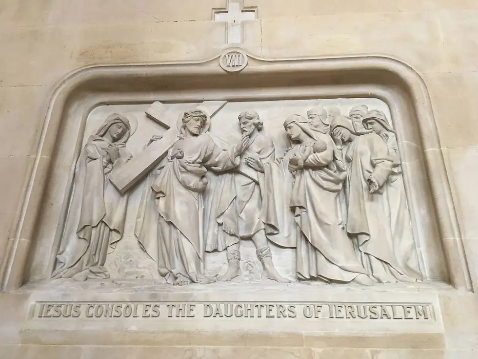Bas-relief sculpture of Jesus consoling women in Jerusalem. Stone texture, beige tones, text reads "JESUS CONSOLES THE DAUGHTERS OF JERUSALEM."