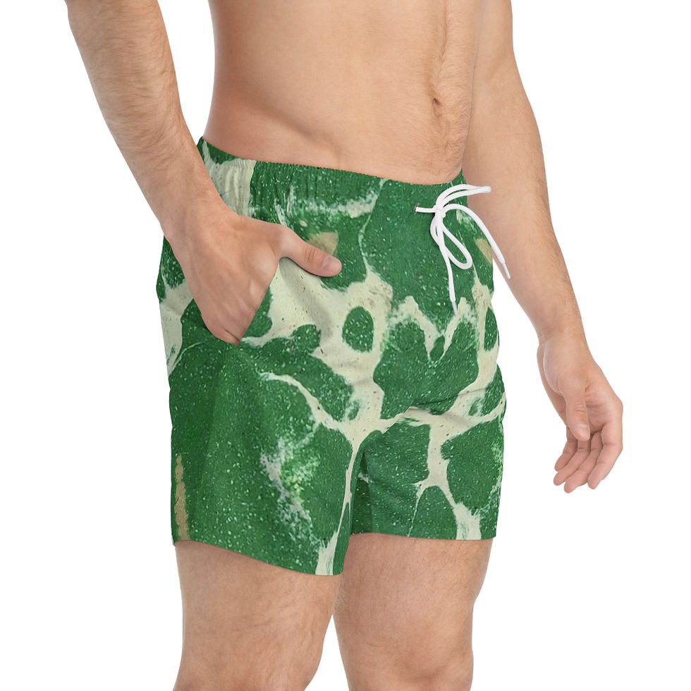 The man stands confidently against a plain backdrop, donning swim trunks featuring a green and white cracked marble effect.