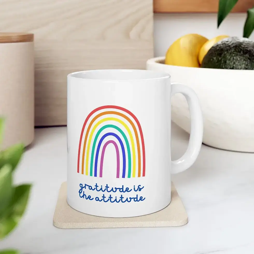 White ceramic mug with colorful rainbow and “Gratitude is the Attitude” text on kitchen counter.