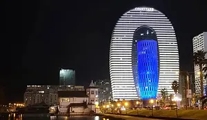 Night view of Batumi skyline featuring the illuminated Courtyard by Marriott building along the waterfront.