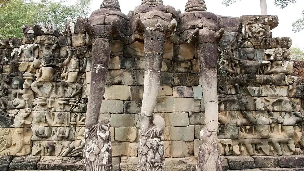 Ancient stone wall with detailed carvings depicting three elephants among various figures at the Terrace of the Elephants in Angkor Thom, Cambodia.