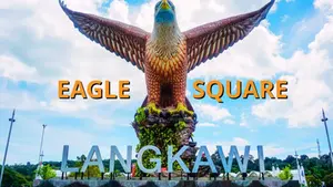 Giant eagle statue with wings spread at Eagle Square, Langkawi. Clear blue sky background, white clouds, and bold text.