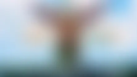 Giant eagle statue with wings spread at Eagle Square, Langkawi. Clear blue sky background, white clouds, and bold text.