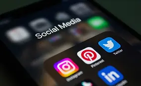 Close-up of a smartphone screen showing a Social Media folder with Instagram, Pinterest, Twitter, and LinkedIn app icons in focus.