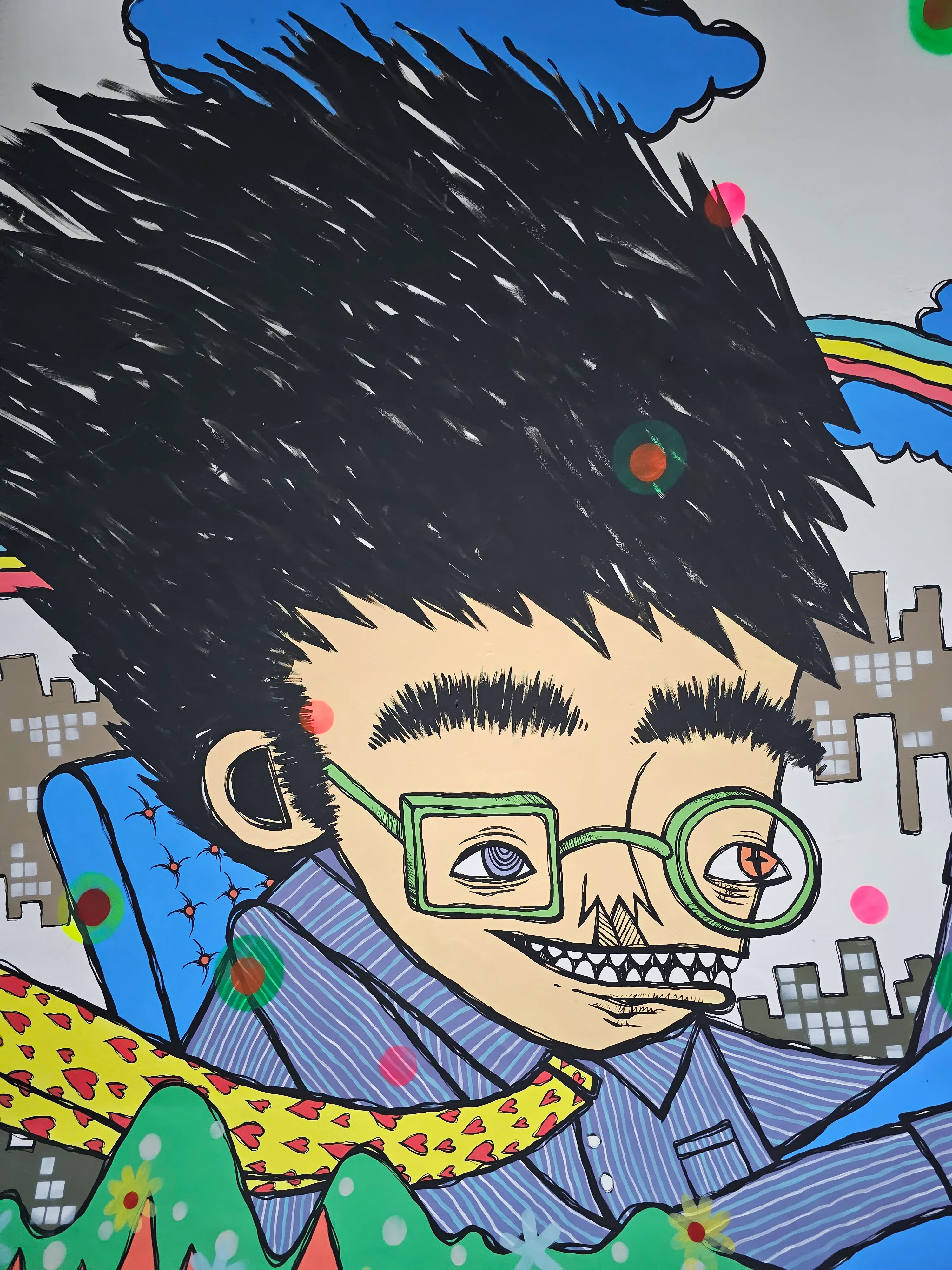 Colorful cartoon drawing of a smiling person with spiky black hair, large green glasses, braces, and a blue shirt. The background features a city skyline, a rainbow, and whimsical abstract elements.