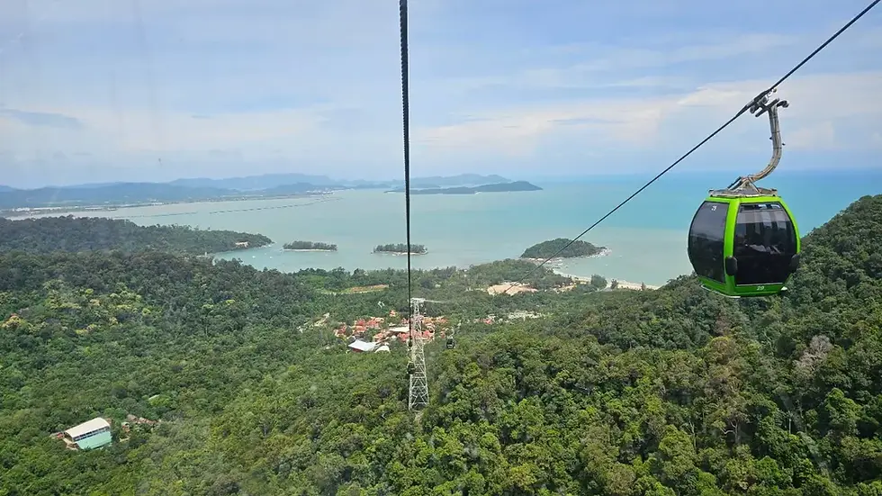 A green cable car ascending over lush rainforest towards the peak of Gunung Machinchang in Langkawi.