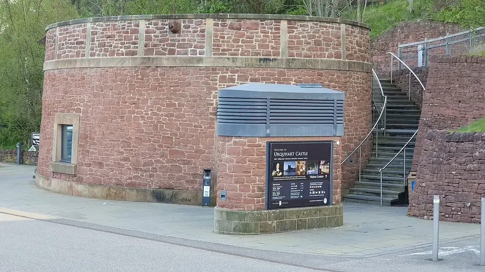 Round brick building with stone steps and green landscape. A sign reads "Welcome to Urquhart Castle." Gray and brown tones dominate.