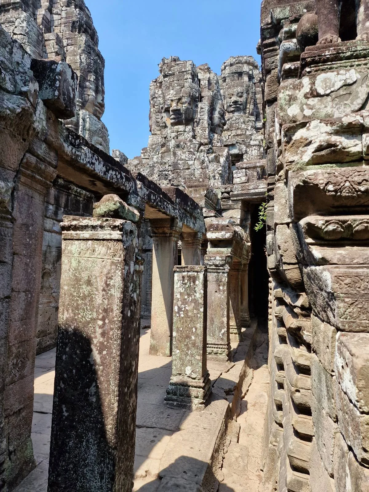 Ancient stone ruins with weathered columns and walls under a clear blue sky, likely part of a historic temple or archaeological site.